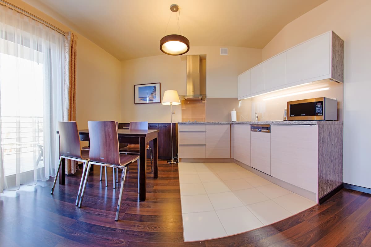 A modern kitchen with a microwave, cabinets, and a dining area with chairs and a table.