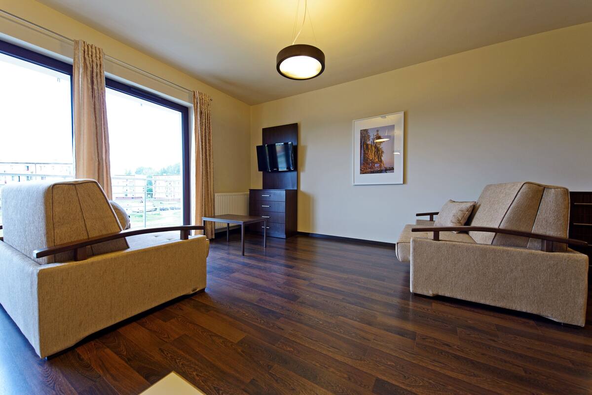 A modern living room with a sofa, a chair, a TV, and a painting on the wall.