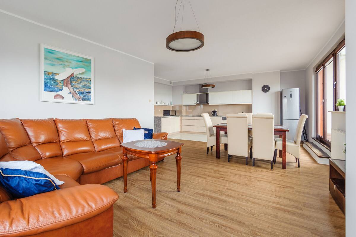 A modern living room with a leather sofa, a wooden coffee table, and a painting on the wall.