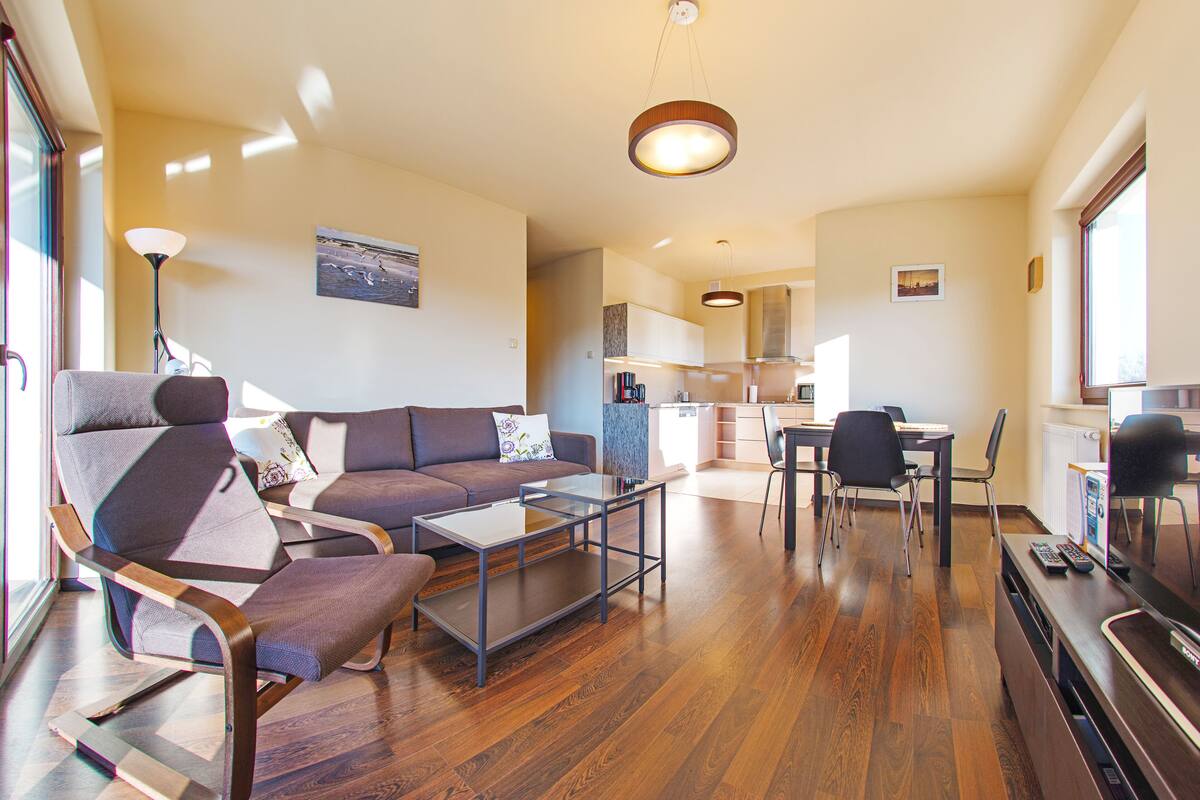 A modern living room with a sofa, chairs, a coffee table, and a dining area with a table and chairs.
