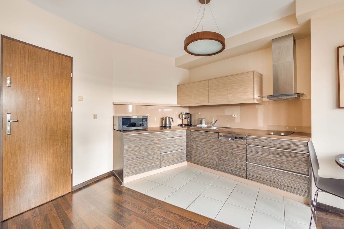 A modern kitchen with wooden cabinets, a microwave, a coffee maker, and a sink.