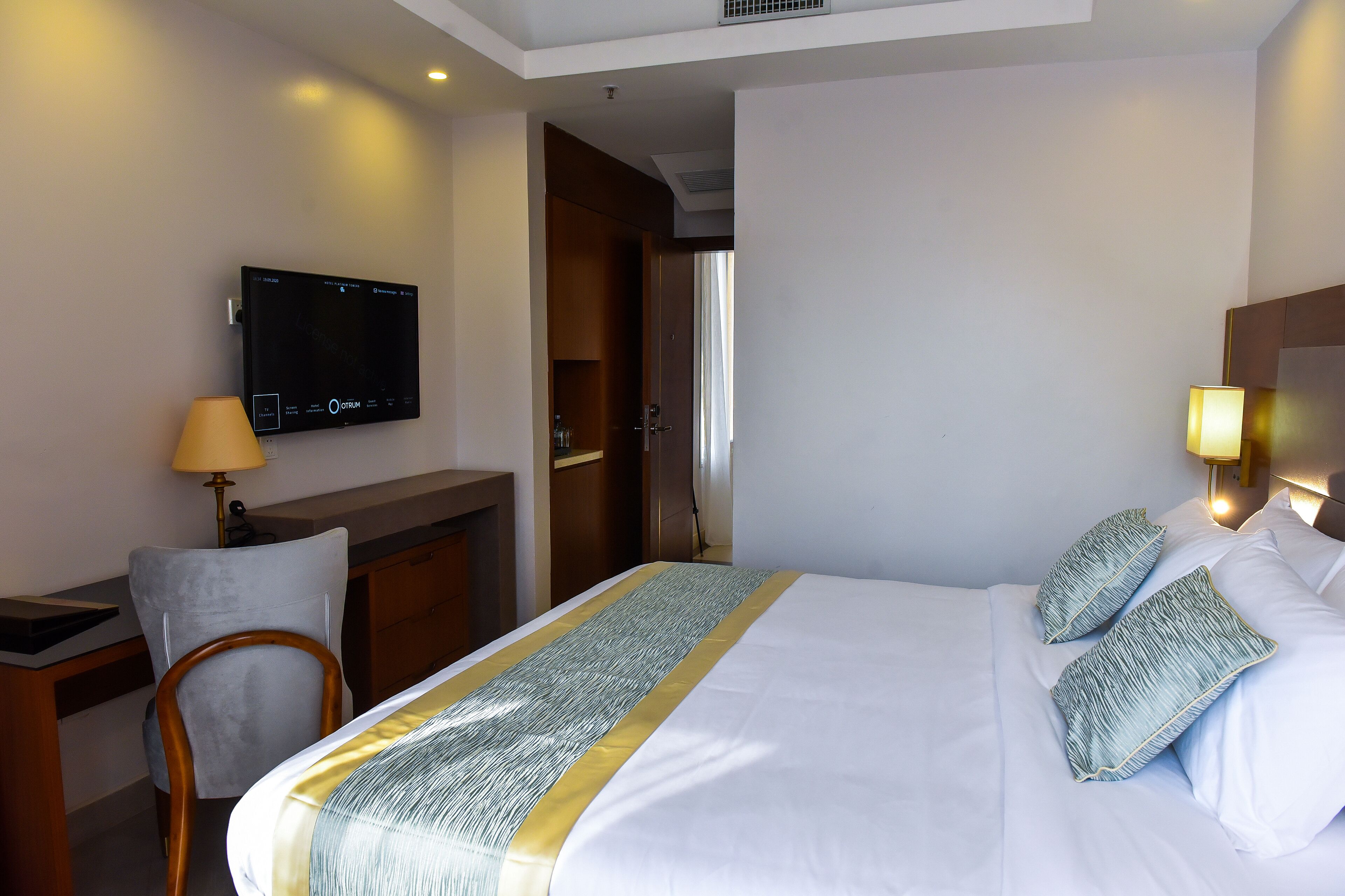 Ein Hotelzimmer mit einem Bett, einem Schreibtisch, einem Sessel, einem Fernseher und einer Lampe.