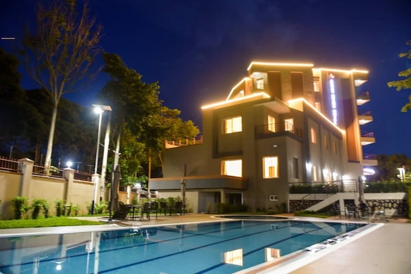 Una piscina al aire libre, sombrillas, sillones reclinables de piscina