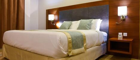 A hotel room with a large bed, two bedside tables, and a wooden headboard.