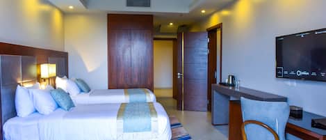 Una habitación de hotel con cama, escritorio, silla y televisor en la pared.