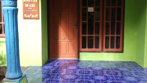 A building entrance with a green wall, a blue pillar, and a tiled floor.