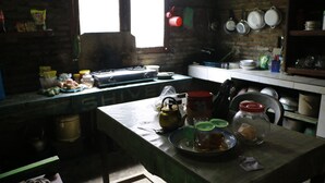 A rustic kitchen with a brick wall, a window, and various kitchen utensils and containers on the counter.