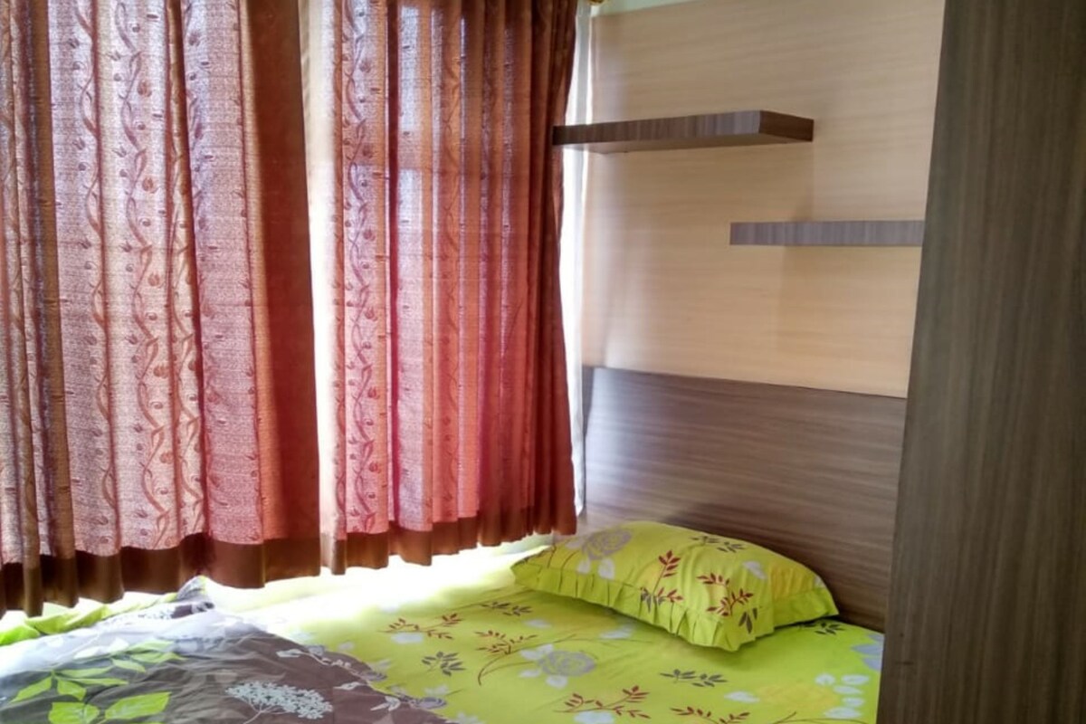 A bedroom with a bed, curtains, a headboard, and a window.