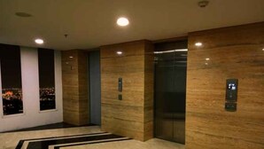 A modern elevator area with marble flooring and wooden paneling. - The Jarrdin Apartment by Berdikari Group (Bandung)