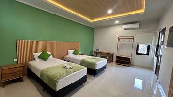 Habitación de hotel con dos camas, un escritorio, un espejo y una pequeña zona de estar.