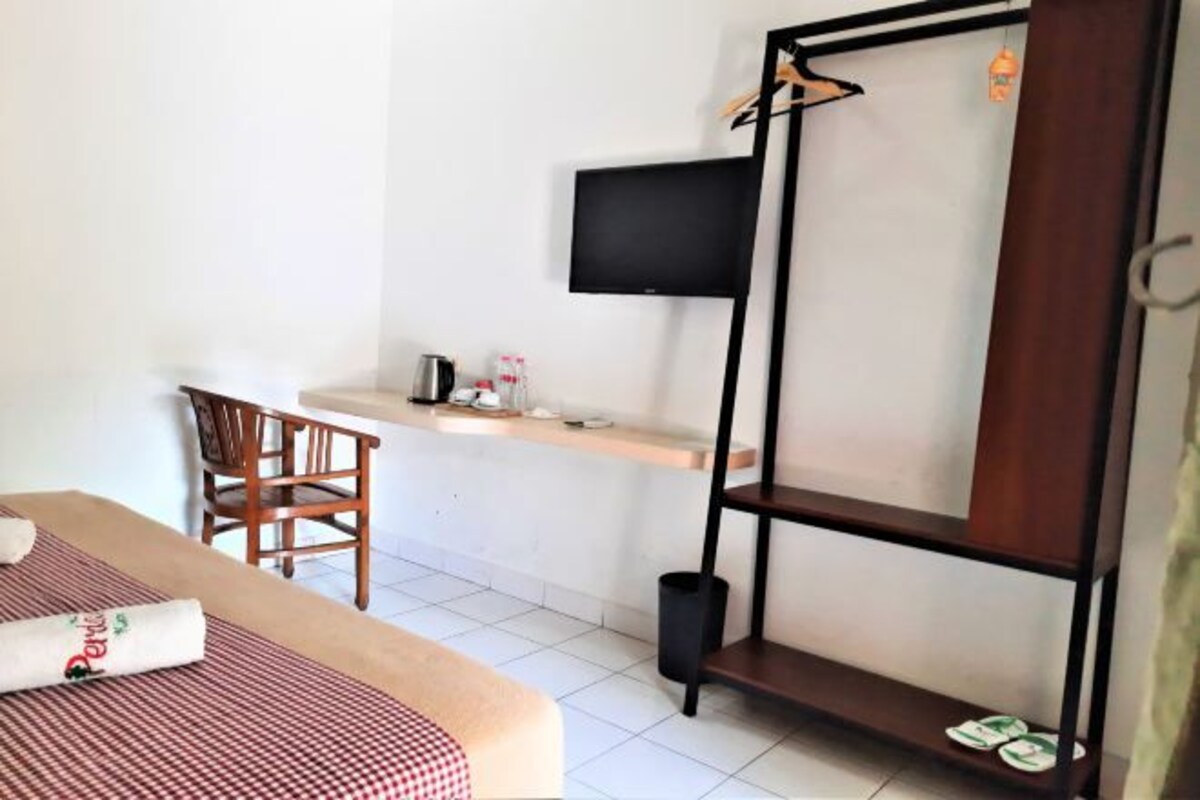 Une chambre d’hôtel équipée d’un lit, d’un bureau, d’une chaise, d’un téléviseur fixé au mur et d’une armoire.