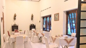 A banquet hall with multiple round tables, white chairs, and chandeliers. - Hotel Perdana (Klaten)