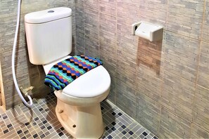 A toilet with a colorful, patterned seat cover, a white tank, and a wall-mounted flush handle. - Hotel Perdana (Klaten)