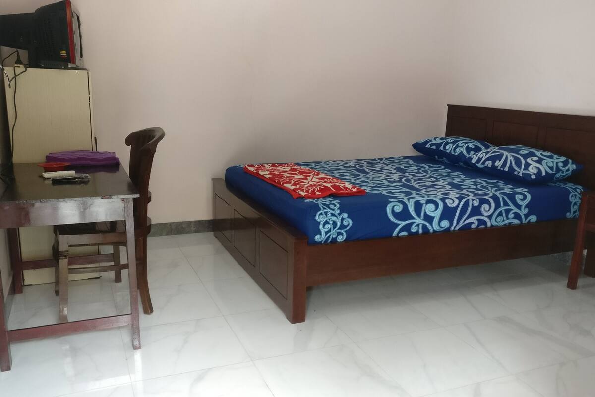 A bedroom with a wooden bed, a desk, and a chair.