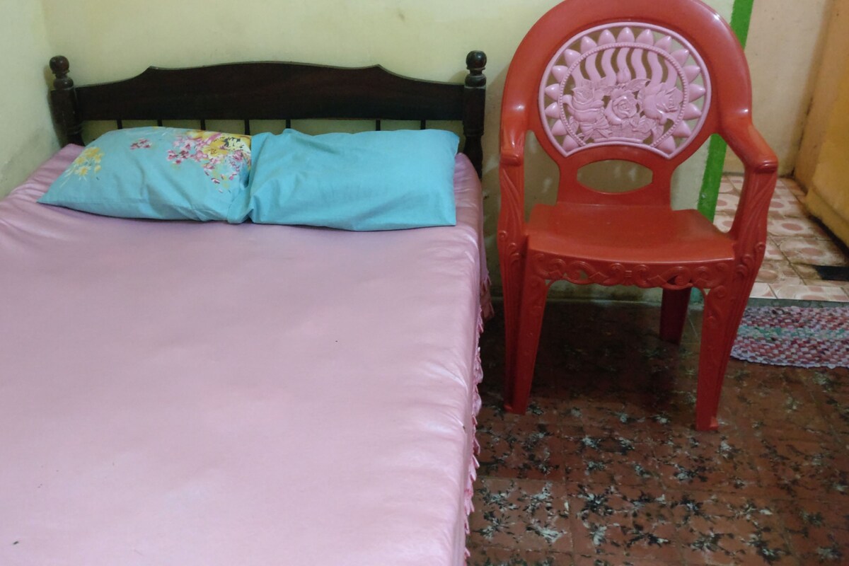 A small room with a bed, a chair, and a patterned floor.