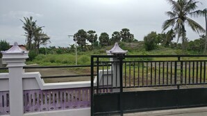 Un área cercada con valla blanca y morada, palmeras y un campo de césped al fondo.
