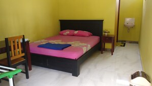 Una habitación con una cama, una silla, una mesita de noche y una lámpara de pared.