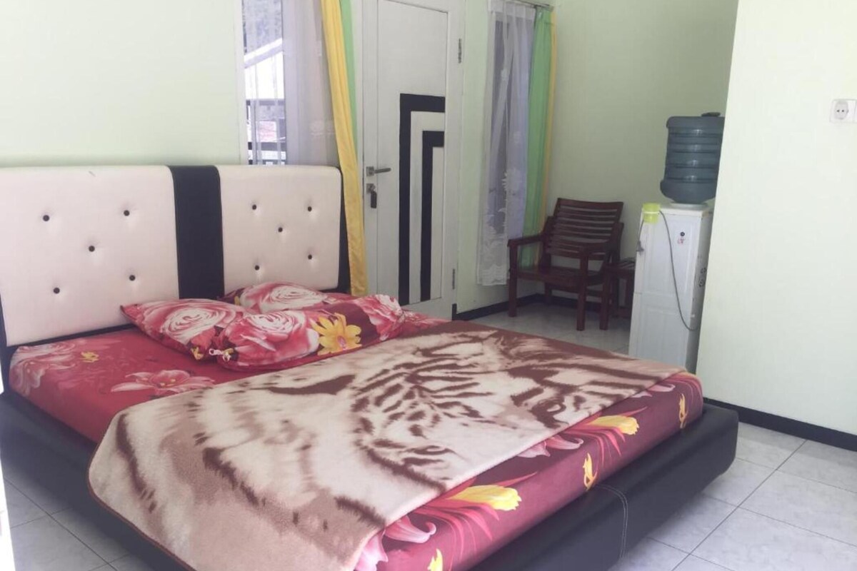A bedroom with a bed, a chair, a water dispenser, and a door.