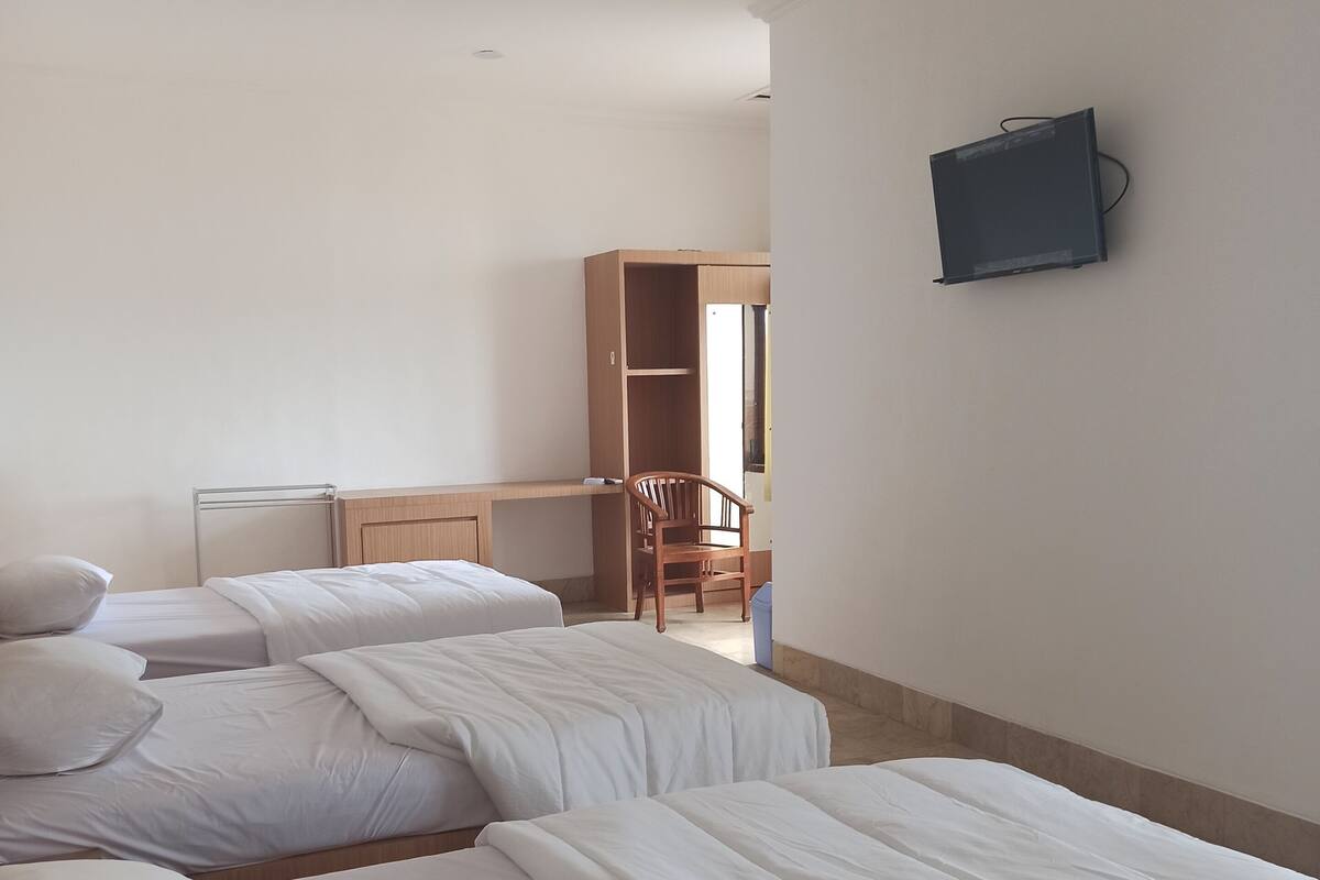 A hotel room with two beds, a desk, a chair, and a television.