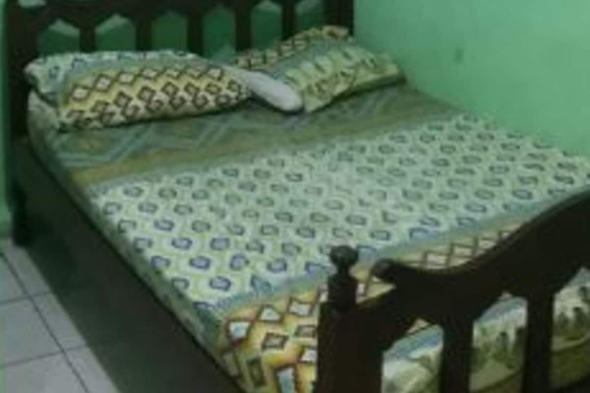A small, single-bed room with a wooden headboard and patterned bedding.