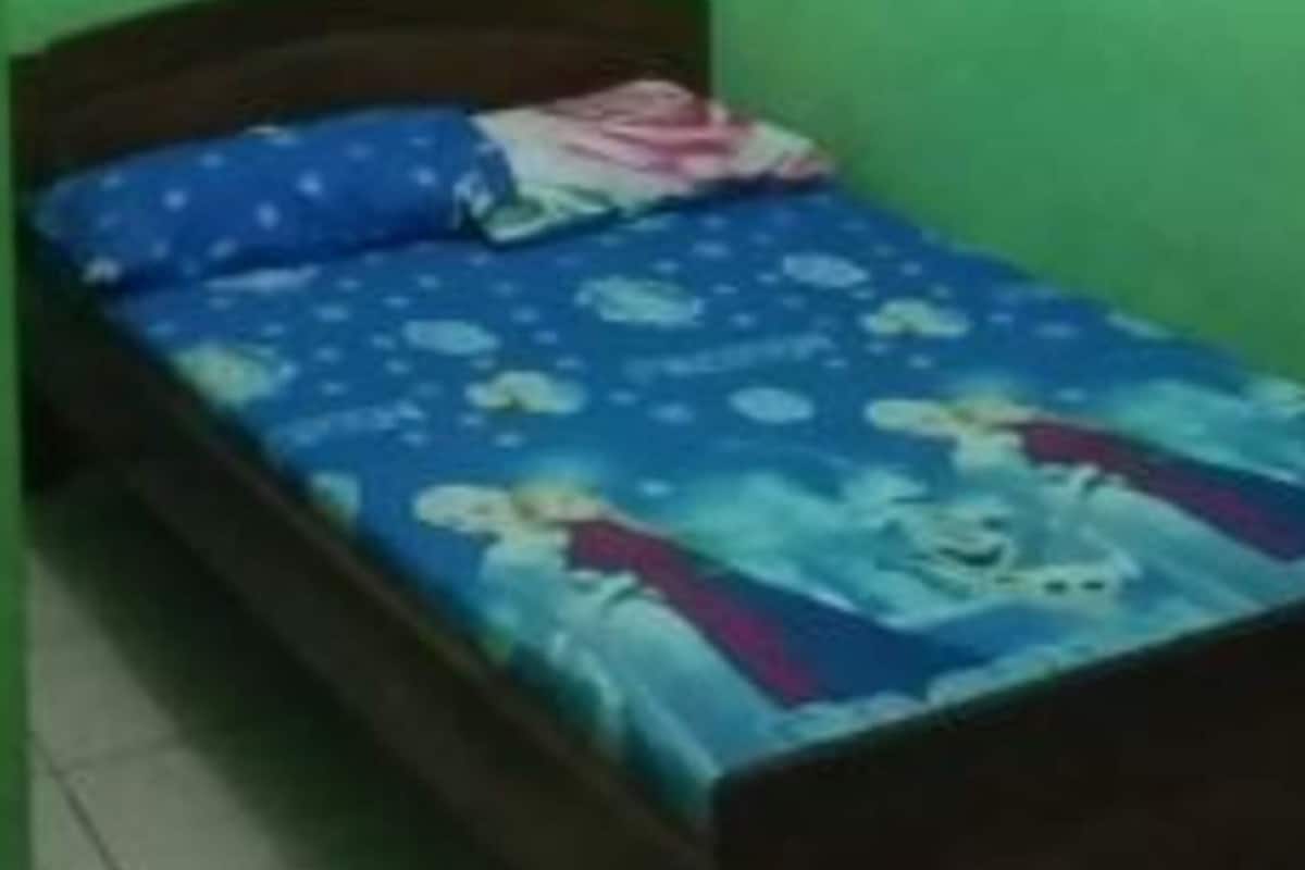 A single bed in a room with green walls and a tiled floor.