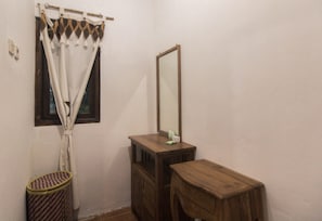 Ein kleines Badezimmer mit einem Holzkosmetikschrank, einem Spiegel und einem Fenster mit Vorhängen.