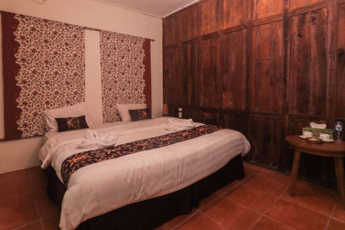 Ein Zimmer mit einem Bett, einem Holzschrank und einem kleinen Tisch mit einer Flasche und einem Karton.
