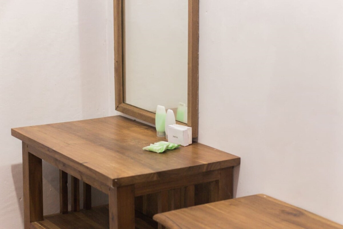 A wooden table with a mirror above it, a tissue box, and a green tissue on the table.