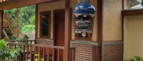 A small building with a tiled roof, a wooden balcony, and a grill attached to the wall.