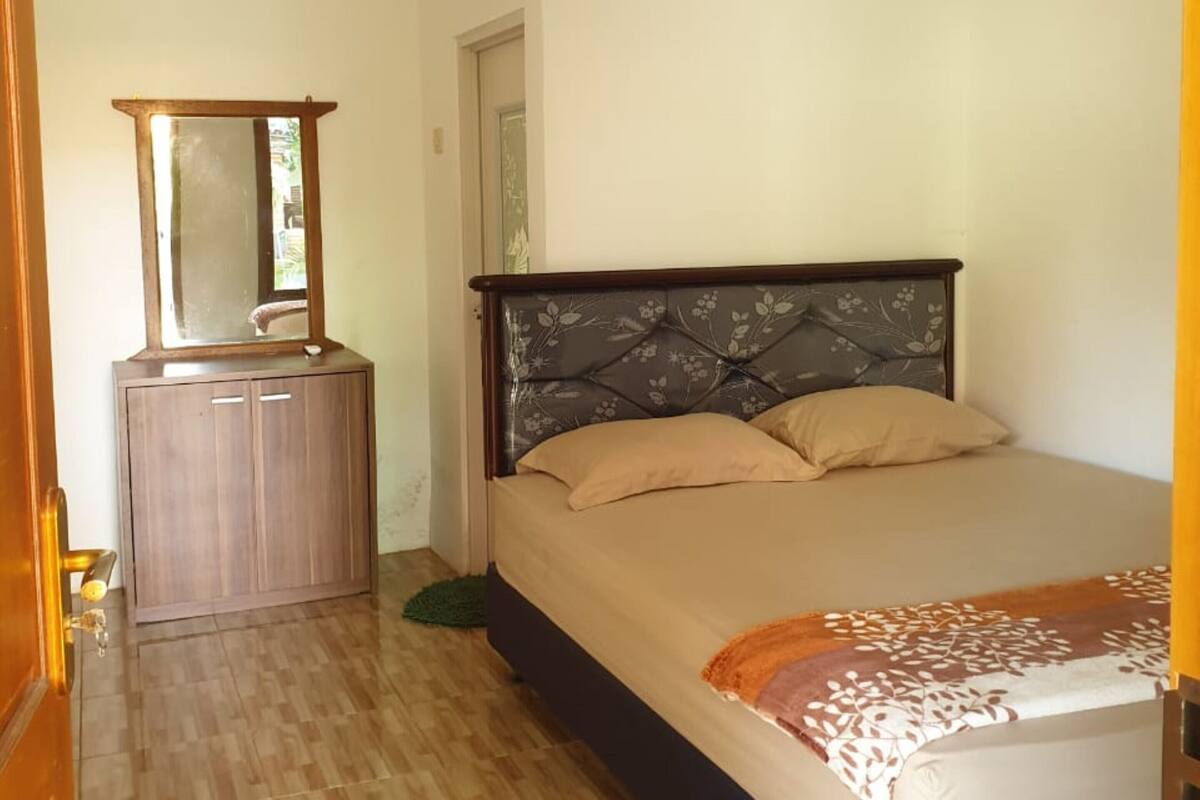 Une chambre à coucher comprenant un lit, une commode, un miroir et un appareil de climatisation.