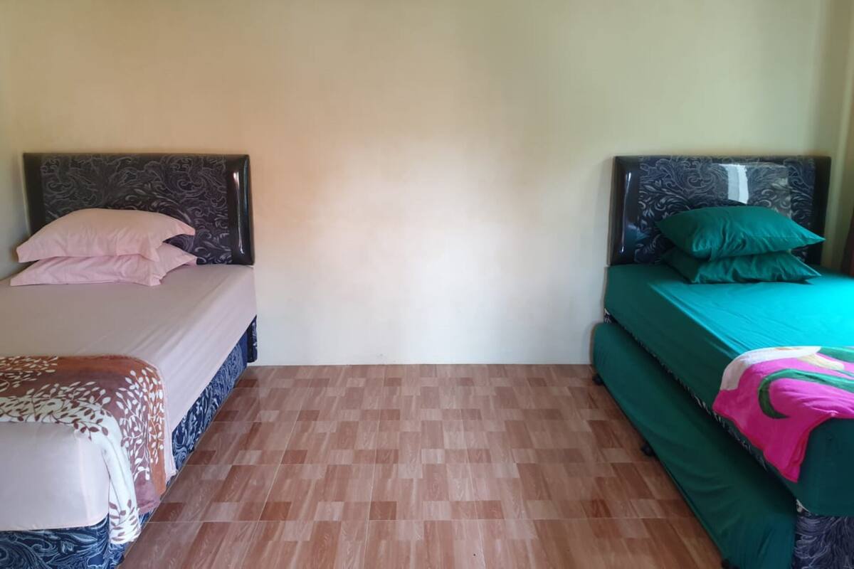 Une chambre avec deux lits, chacun doté d’une tête de lit au design distinctif. La chambre a un sol carrelé et des murs unis.