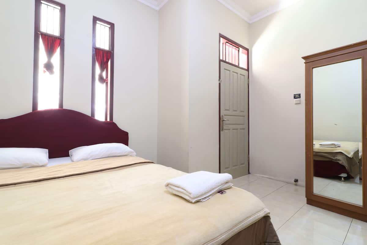 A bedroom with a bed, a wardrobe, and a mirror.