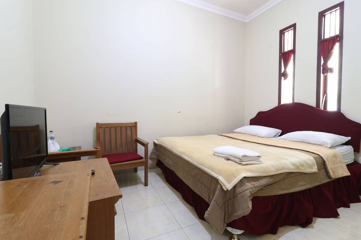 A bedroom with a bed, a chair, a desk, and a television.