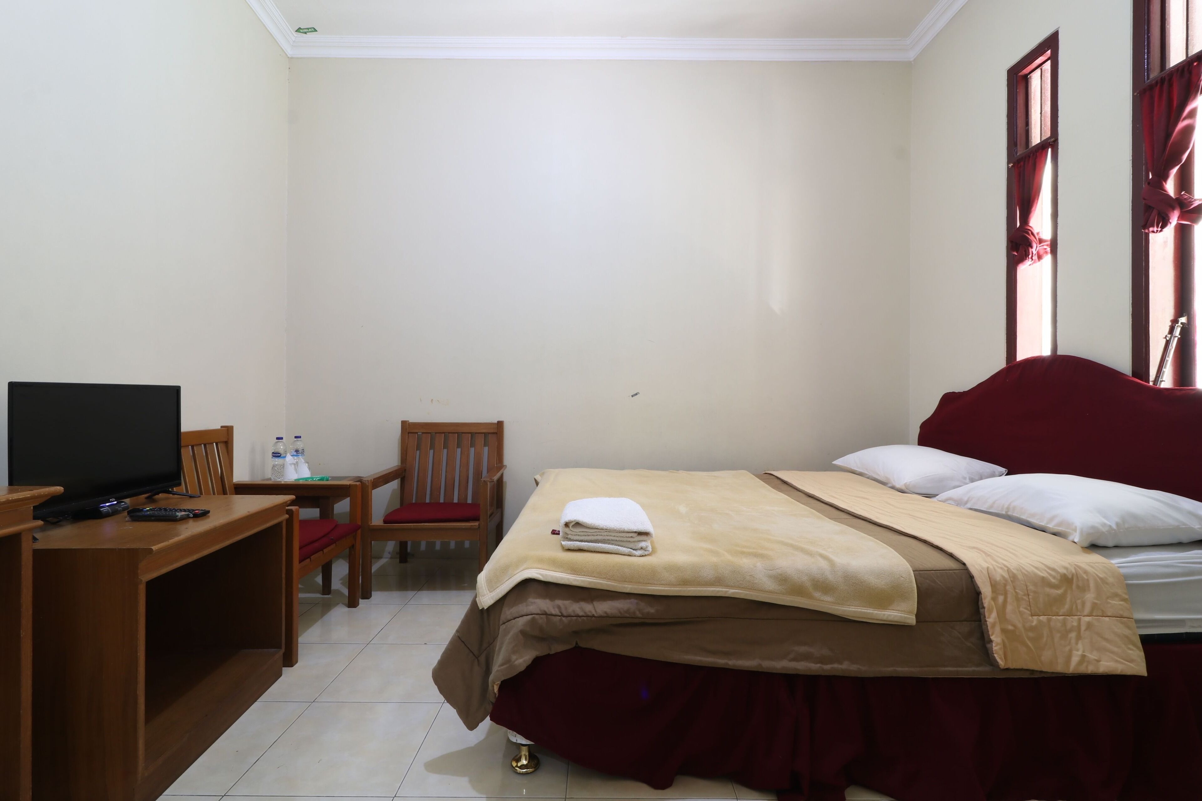 Habitación de hotel con cama, televisión, escritorio, silla y una mesita con botellas.