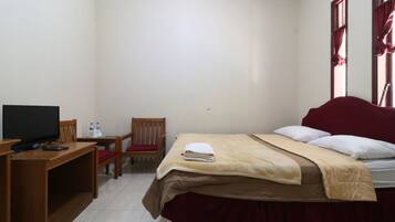 Habitación de hotel con cama, televisión, escritorio, silla y una mesita con botellas.