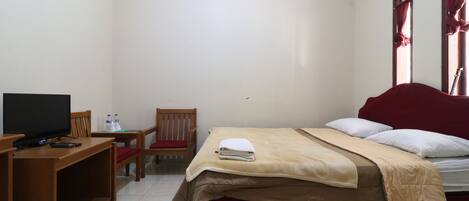 Habitación de hotel con cama, televisión, escritorio, silla y una mesita con botellas.