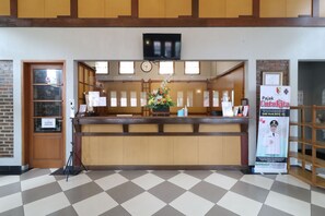 A reception area with a wooden counter, a clock, and a television mounted above. - Kampung Pa'go Resort Hotel (Pasirjambu)