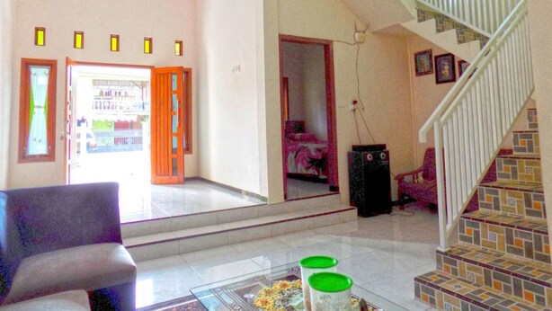 A spacious living area with a staircase, a glass coffee table, and a chair. - Kawah Ijen Homestay (Banyuwangi)