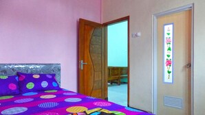 A bedroom with a bed, a wooden door, and a mirror. - Kawah Ijen Homestay (Banyuwangi)