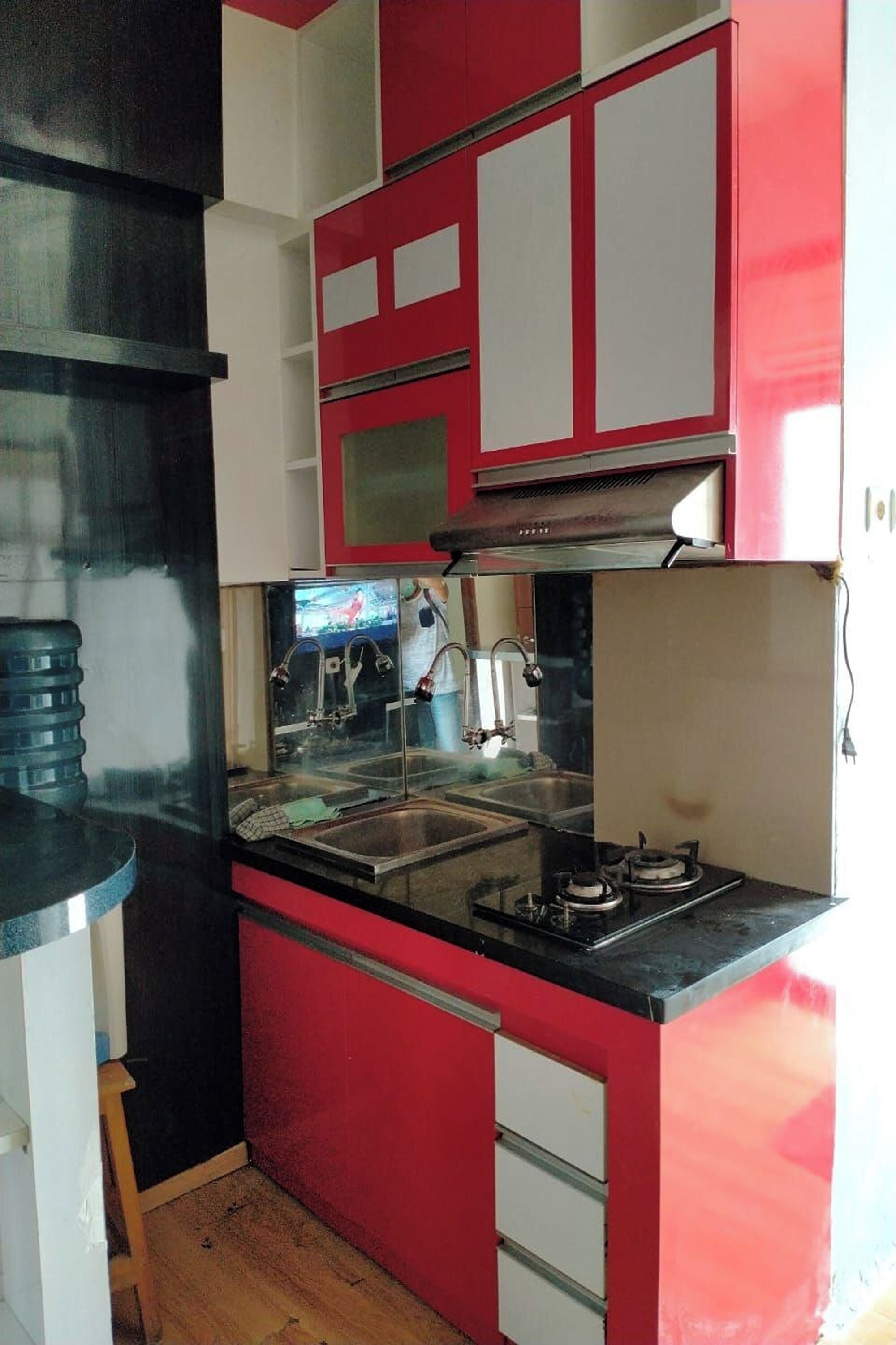 A compact kitchen with red and white cabinets, a stainless steel sink, and a gas stove.