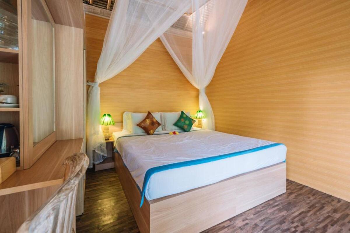 Een slaapkamer met een hemelbed, houten wanden en een nachtkastje met een lamp.