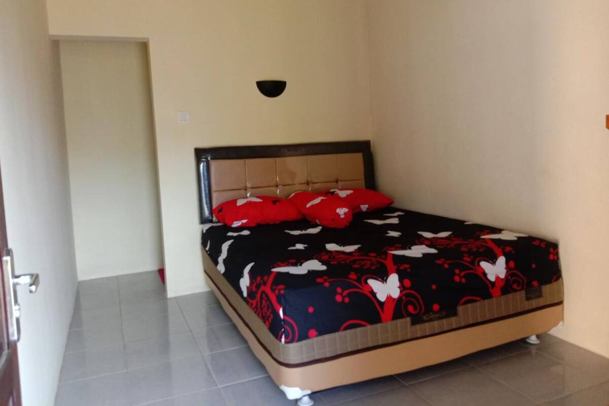 Une chambre à coucher avec un lit, une tête de lit et un luminaire fixé au mur.
