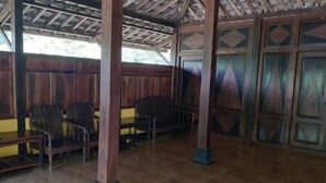 A covered outdoor seating area with wooden benches and columns. - Homestay Ngudi (Mangunan)