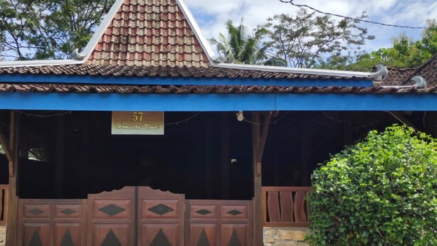 A traditional building with a tiled roof, a sign reading "57 Homestay House," and a wooden gate. - Homestay Ngudi (Mangunan)