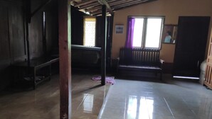 A room with a tiled floor, wooden furniture, a bench, and a window with curtains. - Homestay Ngudi (Mangunan)