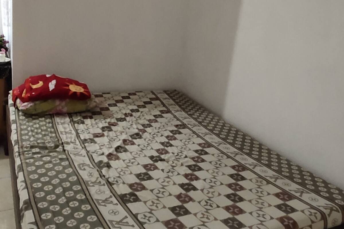 A small room with a patterned bedspread and a red pillow.