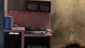 A compact kitchen with a gas stove, a kettle, and a water dispenser. - Homestay Sudiono (Mangunan)