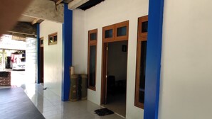 A hallway with a tiled floor, a doorway leading to a room, and a pair of green shoes on the floor. - Homestay Sudiono (Mangunan)