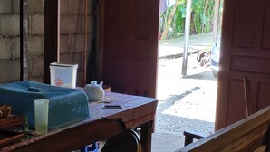 A room with a wooden table, a plastic container, a white pitcher, and a blue chair. - Homestay Sudiono (Mangunan)
