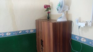 A wooden cabinet with a vase of flowers and a white fan on top. - Homestay Arya Mangunan (Mangunan)